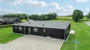 Ein modernes Gebäude mit flachem Dach, rechteckigen Fenstern und einer Schotterauffahrt.