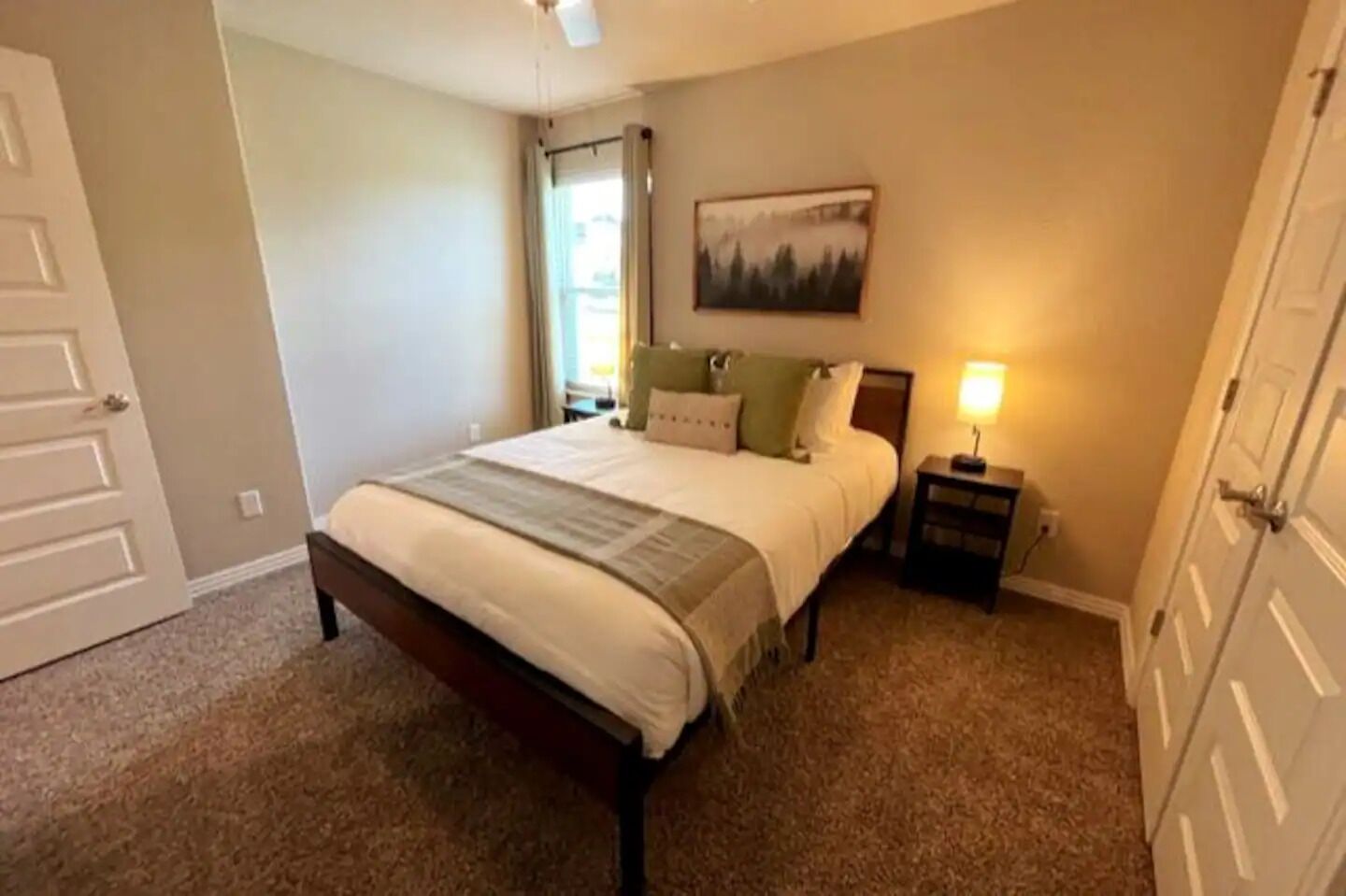 A bedroom with a bed, nightstand, and a painting on the wall.