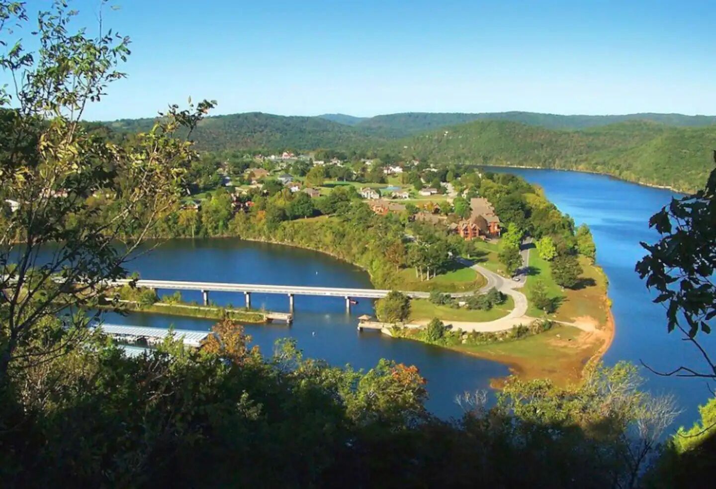 Une rivière traversée par un pont, entourée de verdure et de maisons.