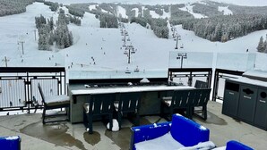 Een sneeuwbedekte buitenruimte met een uitzicht op een skipiste en een berg op de achtergrond.