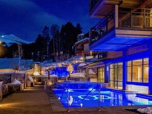 Ein modernes Hotel mit Poolbereich, Außenbereich und Blick auf die verschneite Landschaft bei Nacht.