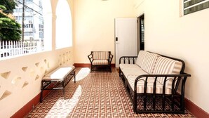 Un balcon doté d’un sol à motifs, d’un canapé, d’une chaise et d’un luminaire suspendu.