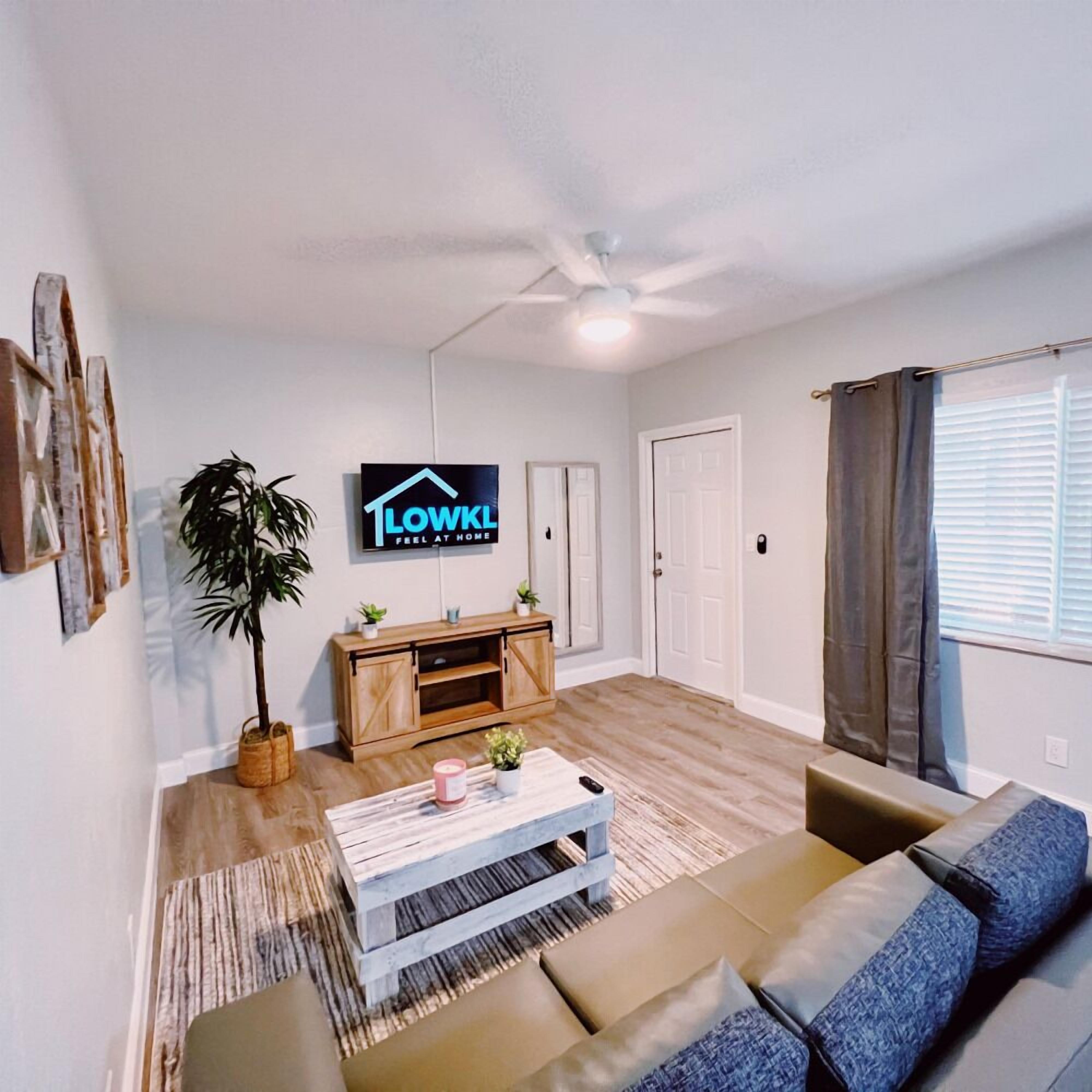 A living room with a sofa, a coffee table, a TV, and a ceiling fan.