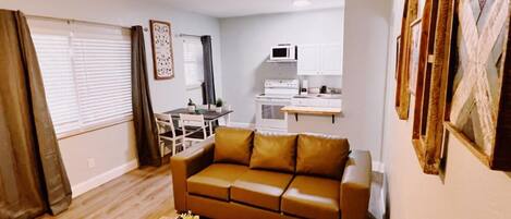 A living room with a brown sofa, a wooden coffee table, and a dining area with a table and chairs.