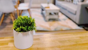 Una sala de estar moderna con un sofá blanco, una mesita de centro y una pequeña planta en maceta sobre piso de madera.