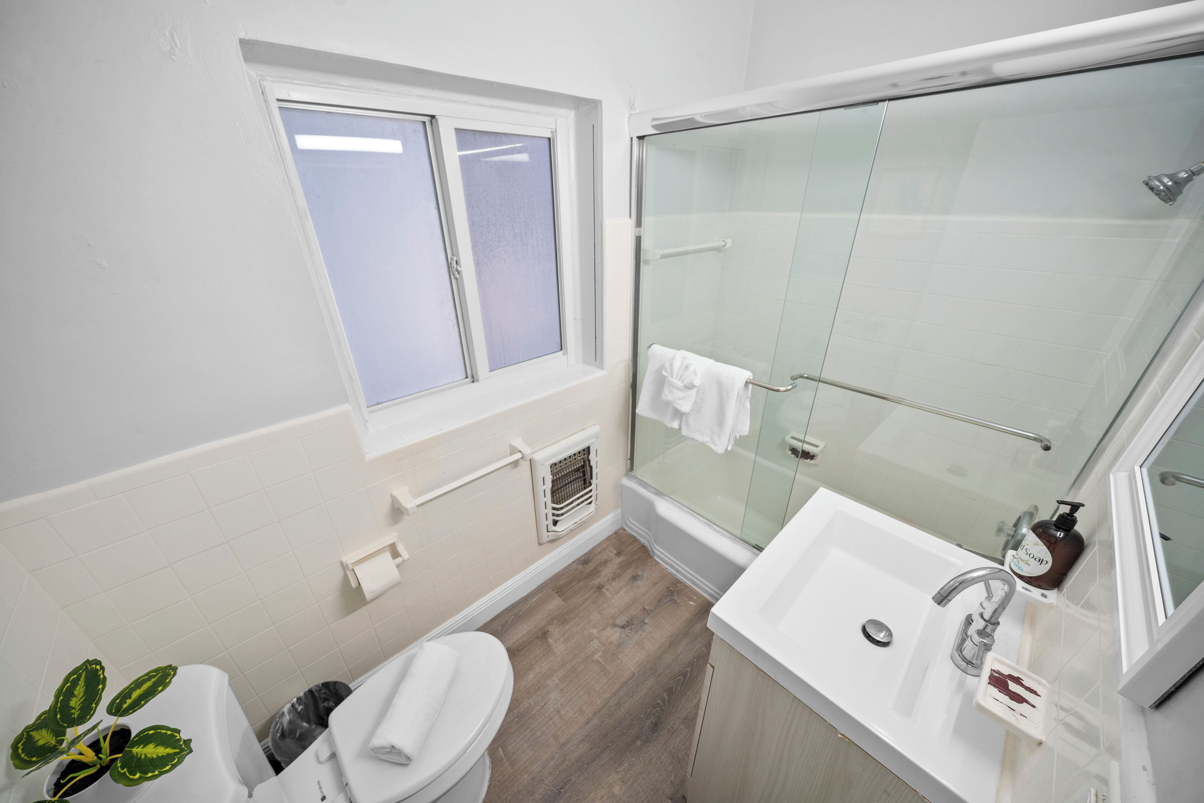 Ein Badezimmer mit Dusche, Toilette, Waschbecken und einem Fenster.