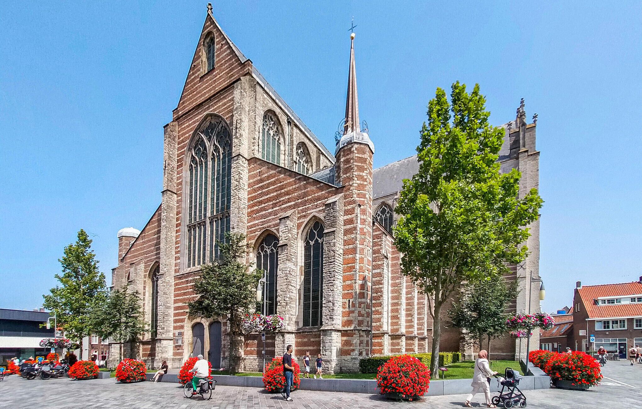A historic church with a tall spire, large arched windows, and a brick facade.