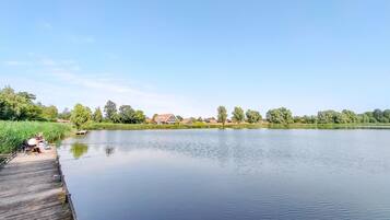 A calm lake with a wooden dock and houses in the background.
