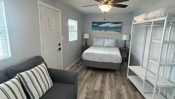 A bedroom with a bed, a ceiling fan, a wardrobe, and a nightstand.