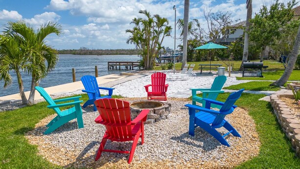 Une terrasse au bord de l’eau, dotée de fauteuils Adirondack, d’un foyer et d’un espace barbecue.