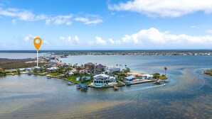 Vue aérienne d’une zone côtière comprenant un port de plaisance, des maisons et une vaste étendue d’eau.