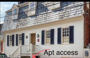 A white building with black shutters, a wooden door, and a small porch. - 18th Cent. Charm in Historic Downtown Annapolis (Annapolis)