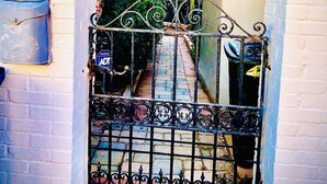 Un callejón cerrado con un portón metálico, un buzón y una pared de ladrillo.