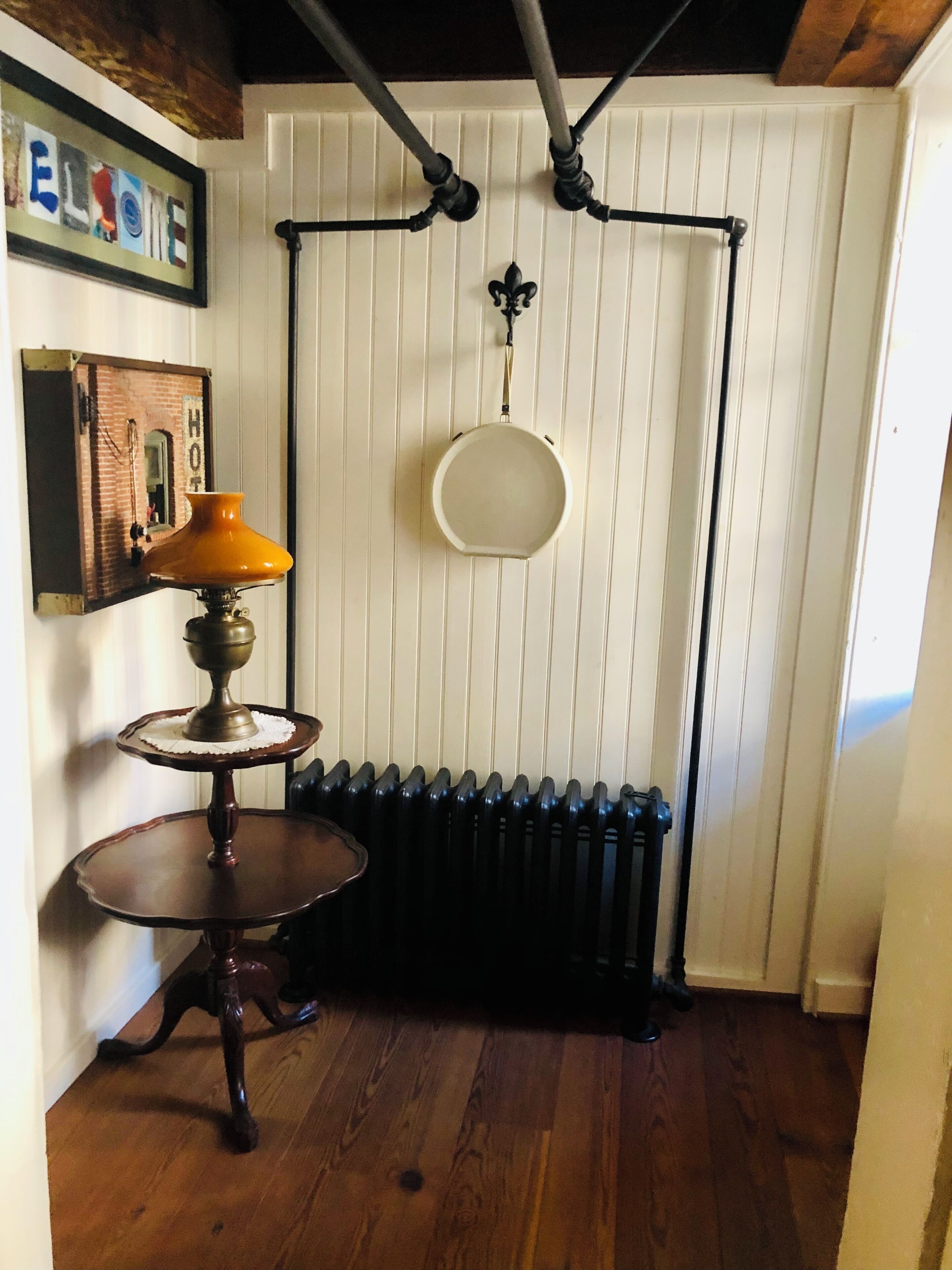 Rincón con un radiador, una lámpara de pared y una pequeña mesa con lámpara.