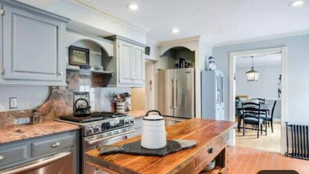 Una cocina con mostrador de madera, estufa y refrigerador.