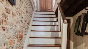 Una escalera con peldaños de madera y una pared blanca a un lado.