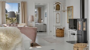 Una habitación acogedora con cama, televisión, chimenea y ventana con cortinas.