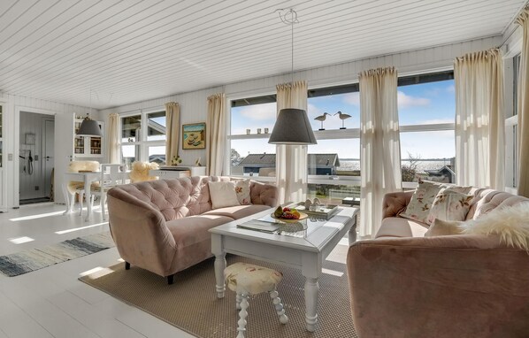 A spacious living room with a large window, a sofa, a coffee table, and a lamp.