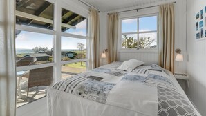 Un dormitorio con una cama grande, dos ventanas y vistas al exterior.