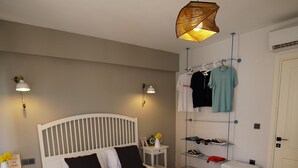 Un dormitorio ordenado con una cama grande, mesitas de noche, un armario y una lámpara colgante.