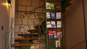 Una escalera con barandilla de metal, una pared de ladrillo y varias cubiertas de libros exhibidas sobre la barandilla.