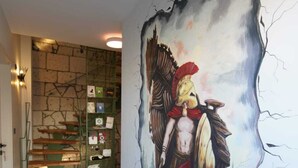 Un pasillo con un gran mural de un guerrero, una escalera de madera y un suelo con diseño.