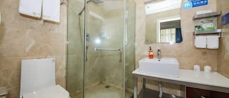 A bathroom with a glass-enclosed shower, a white toilet, a sink with toiletries, and a mirror.