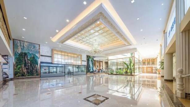 A spacious lobby with a high ceiling, large windows, and a central chandelier. - Xilai Hotel (Yueqing)
