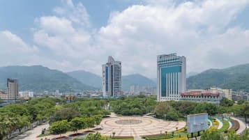 Un paisaje urbano con edificios modernos, un parque circular y montañas al fondo.