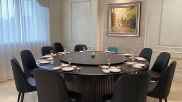 Un salón de conferencias con una mesa redonda, sillas negras y un cuadro en la pared.