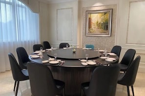 A conference room with a round table, black chairs, and a painting on the wall. - Xilai Hotel (Yueqing)
