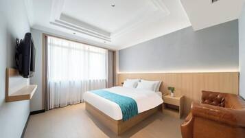 Habitación de hotel con cama, televisión, cabecera de madera, sillón de cuero marrón y ventana con cortinas.