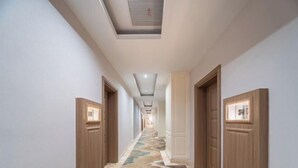 A hallway with wooden doors, a patterned carpet, and recessed lighting. - Xilai Hotel (Yueqing)