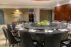 A conference room with a round table, black chairs, and a central decorative plant. - Xilai Hotel (Yueqing)