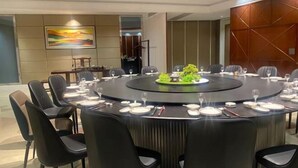 A conference room with a round table, black chairs, and a central decorative piece. - Xilai Hotel (Yueqing)