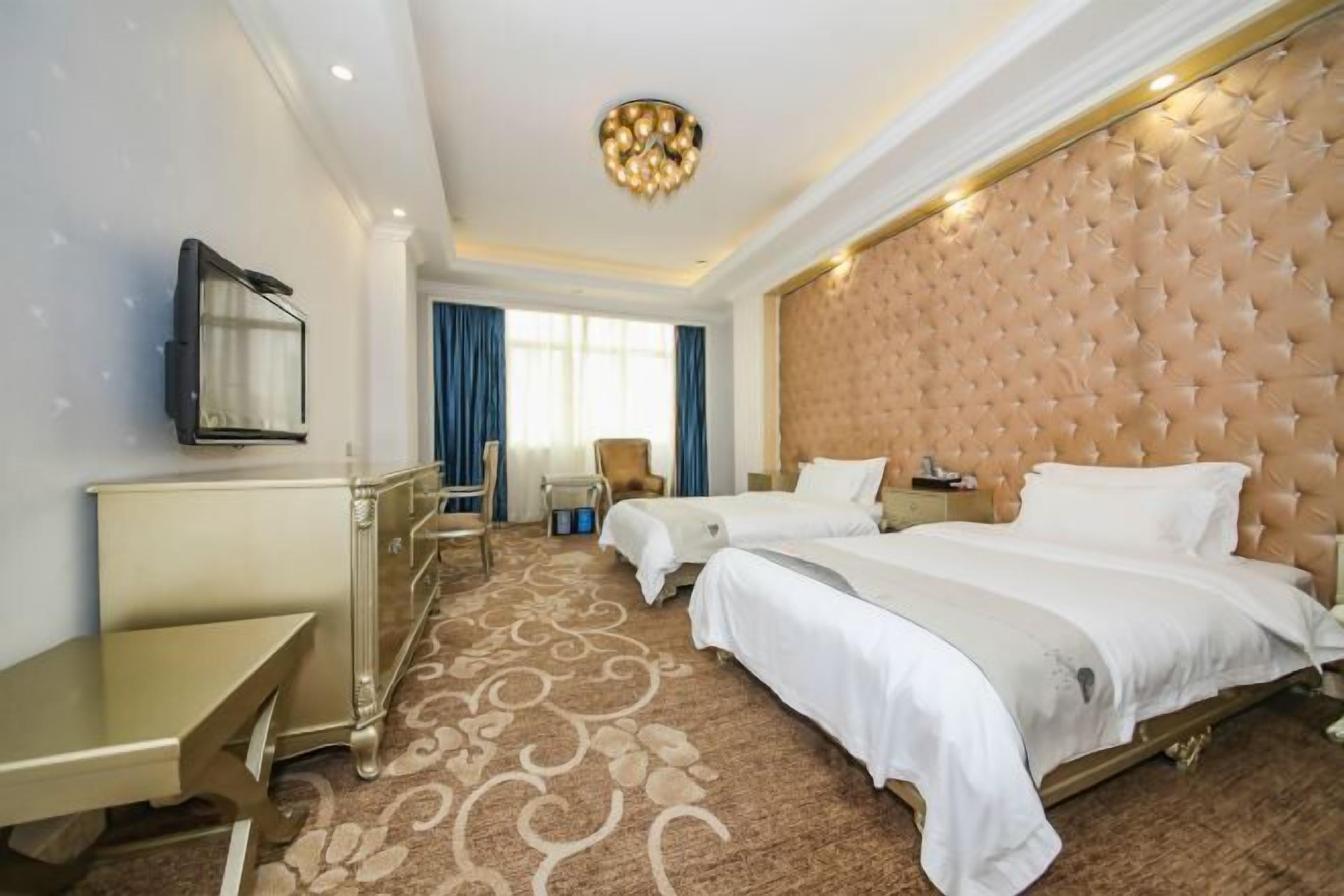Una habitación de hotel con dos camas, un escritorio, una silla y un televisor.