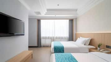 A hotel room with two beds, a TV, a bedside table, a lamp, and a window with curtains.