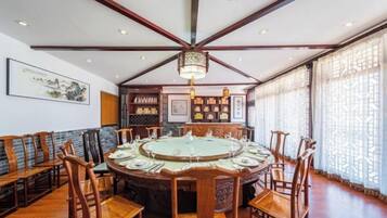 Un comedor tradicional con una mesa redonda, sillas de madera y un ventilador de techo.