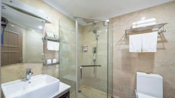 A modern bathroom with a glass-enclosed shower, a white sink, and a toilet.