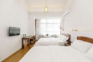 A hotel room with two beds, a desk, a chair, a television, and a window with curtains.