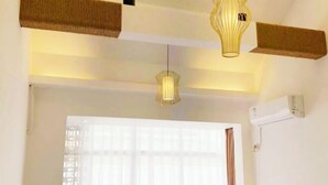 Quarto com uma janela ampla, luminária pendente e ar-condicionado fixado na parede.