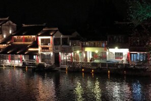 Um edifício tradicional com vários andares, uma varanda e um reflexo na água.