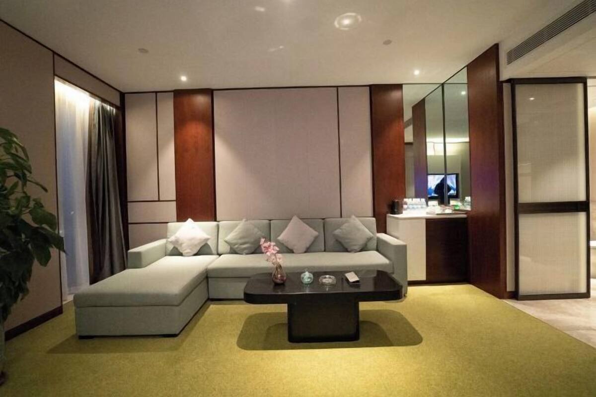 A modern living room with a sectional sofa, a coffee table, and a television in the background.