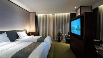 A hotel room with two beds, a television, a desk, and a window with curtains.
