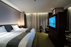 Een hotelkamer met twee bedden, een televisie, een bureau en een raam met gordijnen.