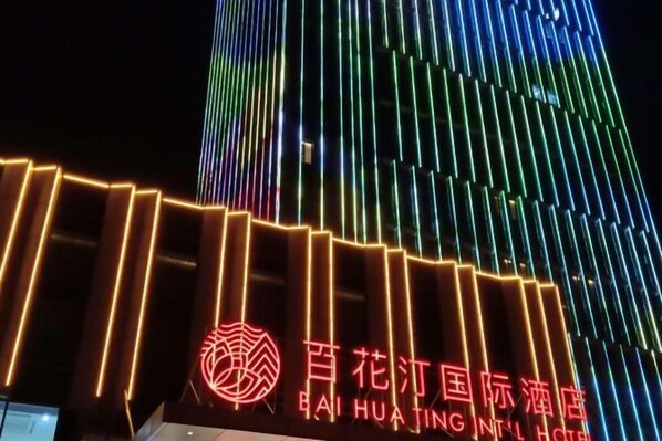A hotel with a prominent vertical light display and a sign indicating it is the Baihuajing International Hotel.