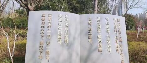 A stone monument with inscriptions, surrounded by trees and shrubs.