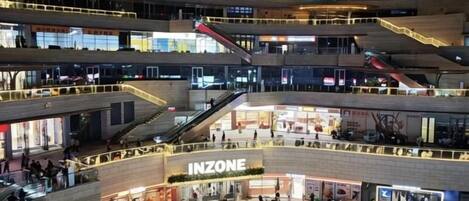 A multi-level commercial building with a central open plaza, escalators, and various shops including an INZONE store.