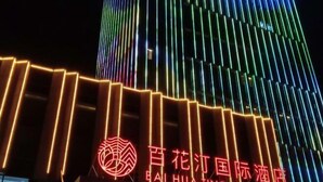 Un hotel con fachada moderna que presenta tiras verticales de luz y un logotipo destacado.