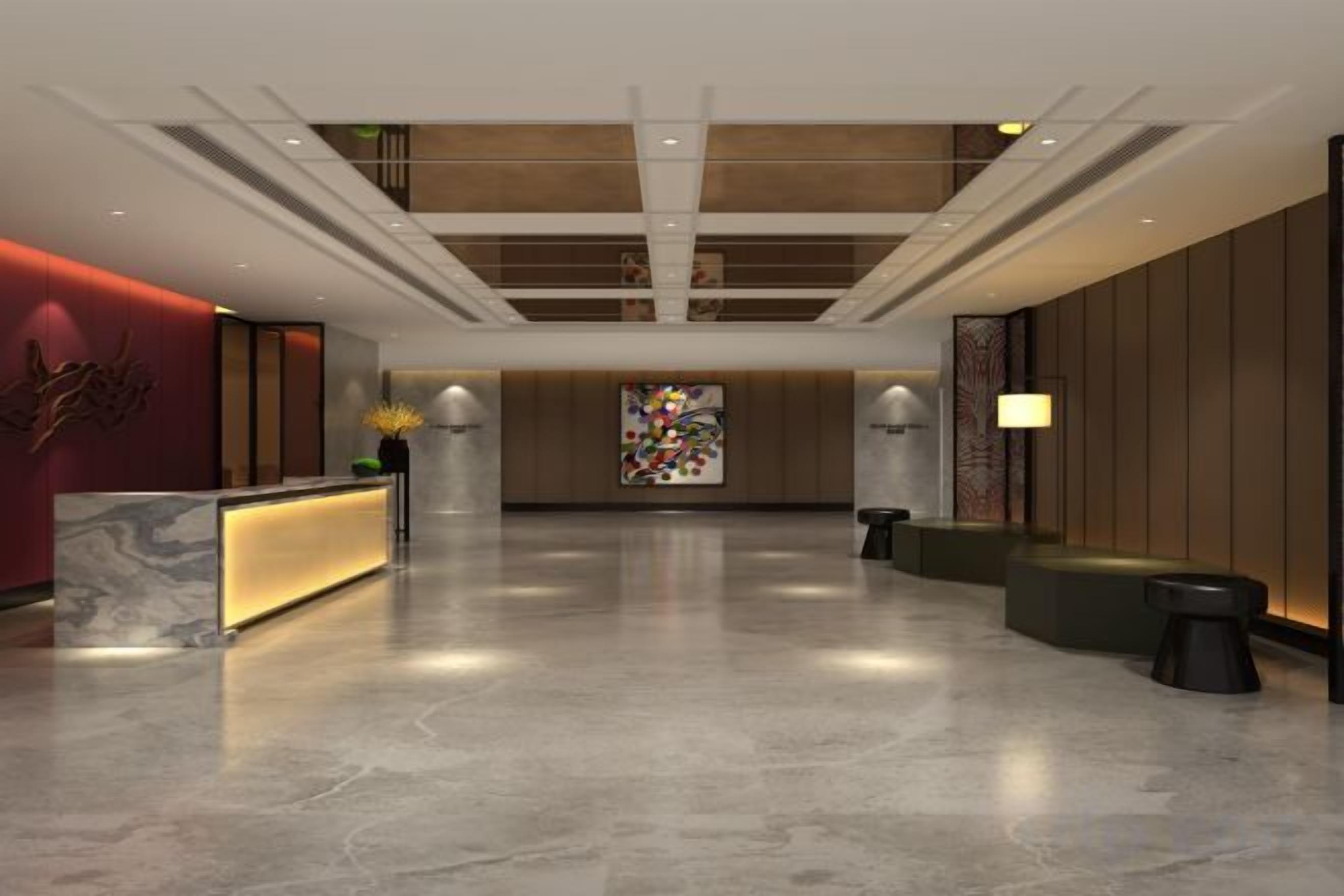 A modern hotel lobby with a reception desk, seating area, and a large open space.